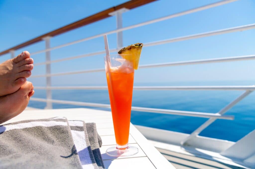 Person of legal drinking age on a cruise ship with drink sitting on a table over looking ocean